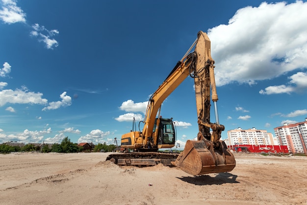 Une excavatrice sur un chantier de construction contre un ciel bleu