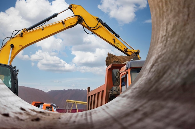 Une excavatrice charge de la terre ou du sable dans un camion-benne Aménagement d'une fosse Terrassement à l'aide d'équipements de construction lourds