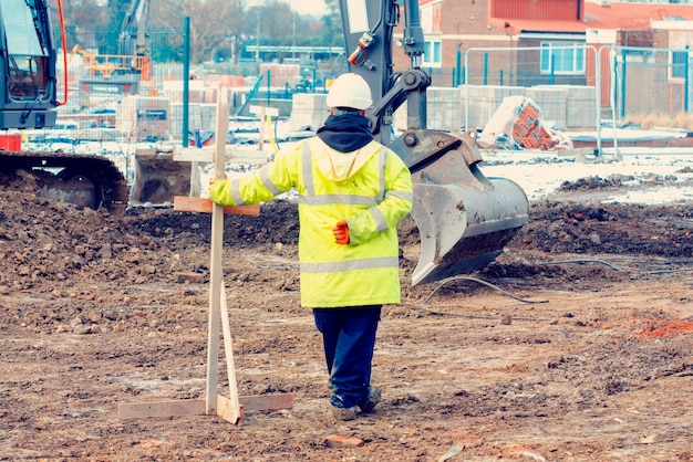 Excavatrice creusant et nivelant le sol sur le chantier de construction D