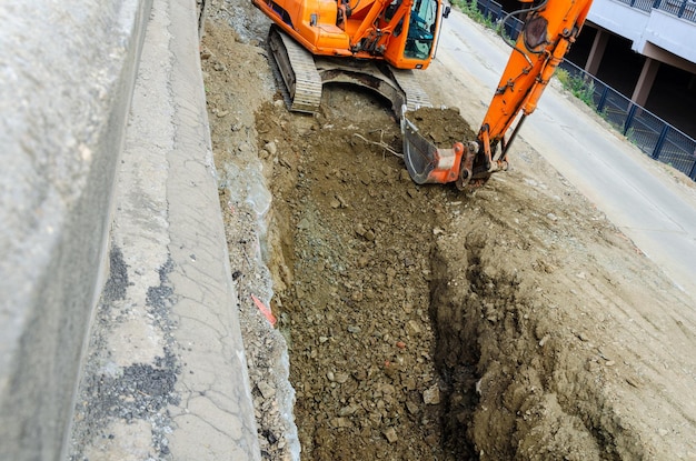 Une excavatrice creuse un fossé dans la rue.