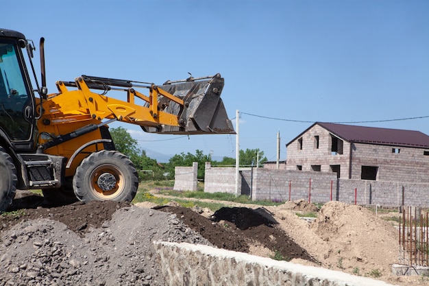 Excavatrice et nouveau bâtiment dans le domaine. construire une maison