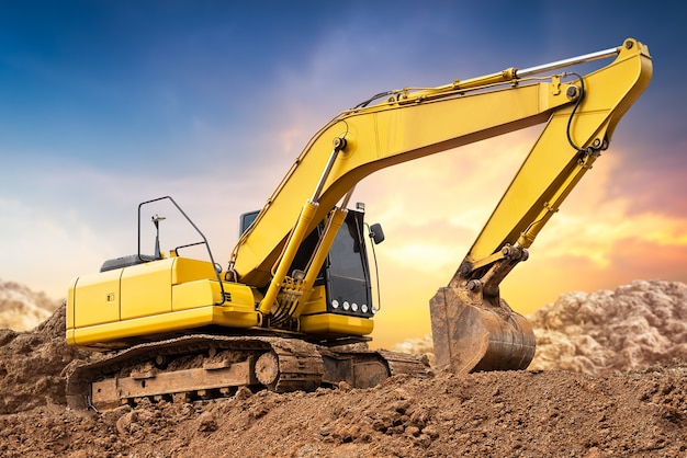 Excavatrice pelleteuse sur le sol sur un chantier de construction au coucher du soleil