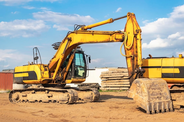 Excavatrice puissante sur un chantier de construction contre un ciel bleu nuageux Matériel de construction de terrassement Machines de construction modernes