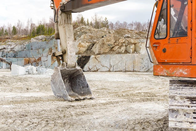 L'excavatrice sale orange se tient dans une carrière pour l'extraction du marbre