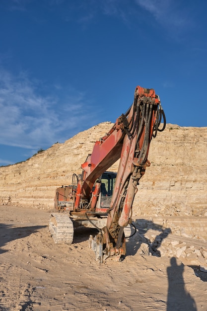 L'excavatrice se dresse sur le fond d'une carrière de pierre.