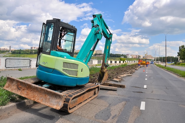 L'excavatrice de travaux routiers enlève le vieux trottoir