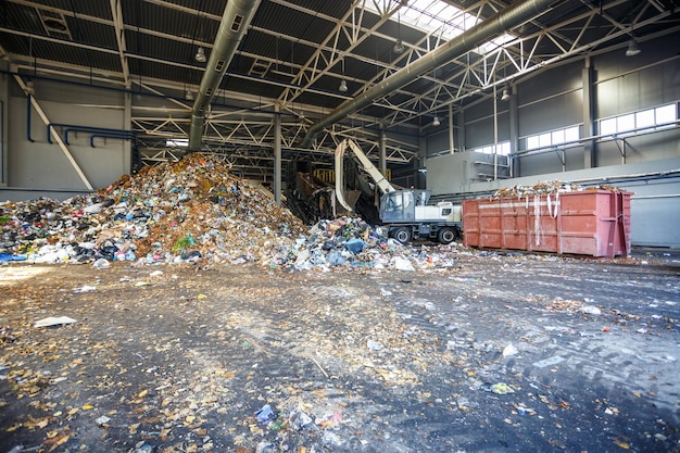 Excavatrice sur le tri primaire des ordures à l'usine de traitement des déchets Collecte séparée des ordures Recyclage et stockage des déchets pour une élimination ultérieure Entreprise de tri et de traitement des déchets