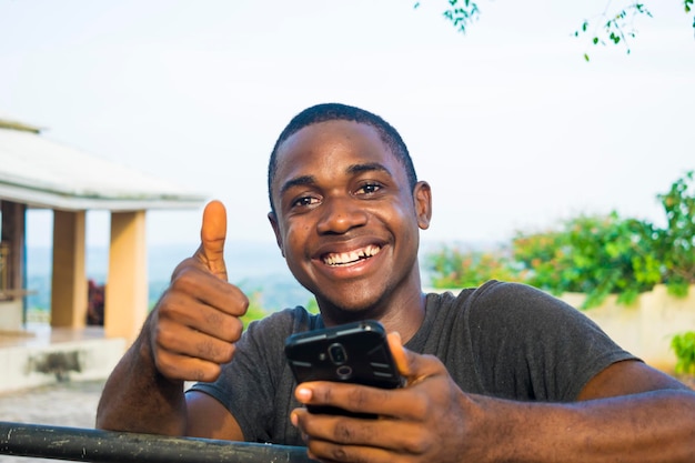 Excité afro-américain millénaire Jeune homme tenir un smartphone se sentir euphorique en lisant de bonnes nouvelles ravi heureux homme noir utiliser le triomphe du téléphone portable gagner à la loterie en ligne