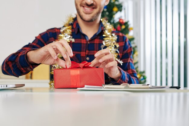 Excité entrepreneur souriant ouverture cadeau de Noël au bureau