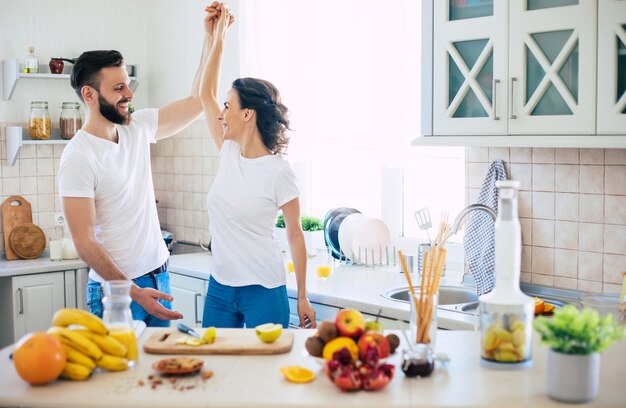 Excité heureux beau jeune couple amoureux cuisiner dans la cuisine et s'amuser ensemble en dansant et souriant