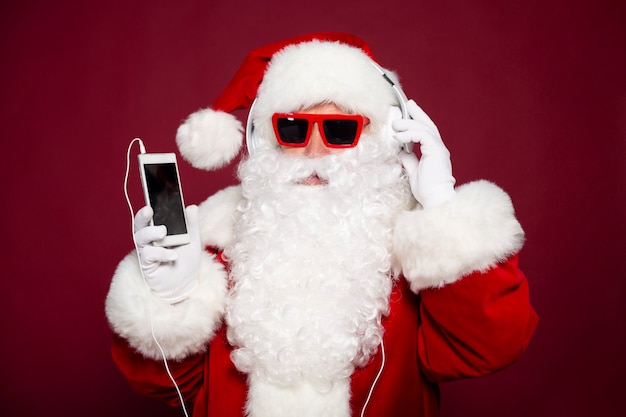 Excité heureux hipster Santa Claus dans des écouteurs et des lunettes de soleil s'amuse à la fête