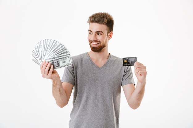 Excité heureux jeune homme tenant de l'argent et une carte de crédit.