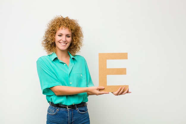 excité, heureux, joyeux, tenant la lettre E de l'alphabet pour former un mot ou une phrase.