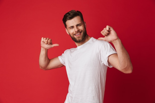 Excité jeune bel homme pointant vers lui-même.