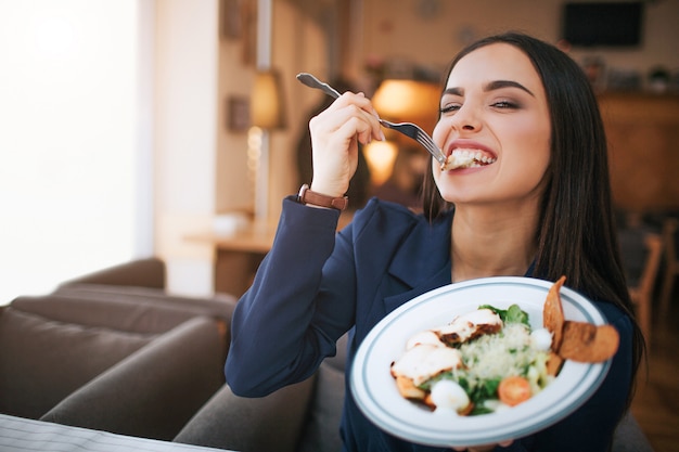 Excité jeune femme mordre un morceau de salade et en profiter