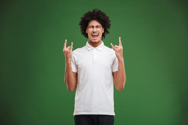 Excité jeune homme bouclé africain fait un geste de rock.