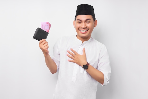 Excité jeune homme musulman asiatique tenant un portefeuille plein d'argent comptant isolé sur fond blanc Les gens concept de style de vie islamique religieux