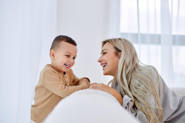 Excité mère de famille européenne américaine et enfant garçon s'amusant sur le canapé jeune femme souriante ...