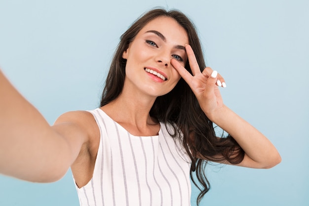 Excité mur isolé jeune femme faire un selfie par caméra.