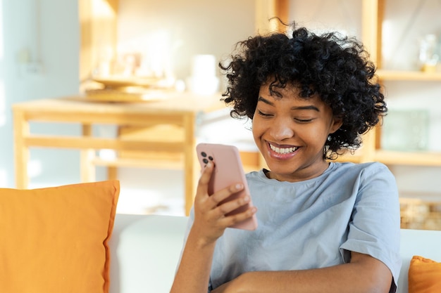 Excitée heureuse jeune femme afro-américaine noire tenant un téléphone portable en riant se sentant la joie de se faire foule