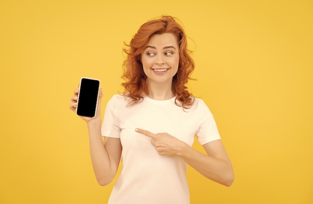 Excitée jeune femme isolée sur fond jaune à l'aide d'un téléphone portable montrant un geste ok
