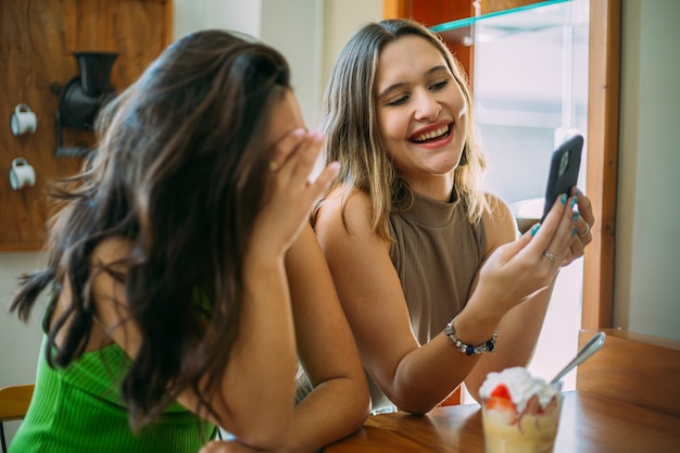 Excitées belles deux femmes latines regardent une vidéo amusante sur un téléphone portable moderne