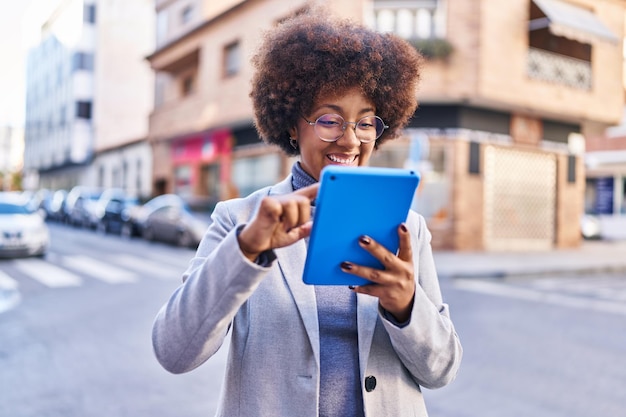 Exécutif de femme afro-américaine souriant confiant à l'aide du pavé tactile dans la rue