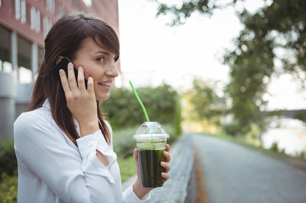 Exécutif parlant au téléphone mobile tout en ayant du jus