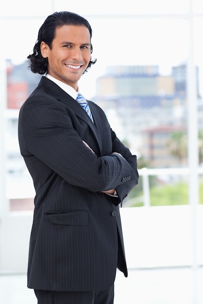 Exécutif souriant traversant ses bras tout en regardant la caméra