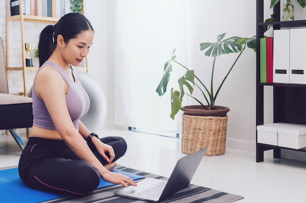 Exercice de belle femme asiatique à la maison et regarder la vidéo de formation sur ordinateur portable.