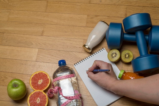 Photo exercice d'entraînement vigueur et santé haltères en plastique cahier eau minérale et jus de fruits et stylo