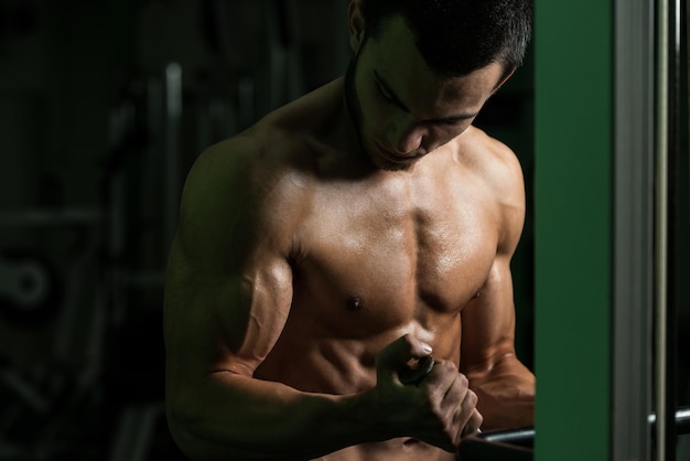 Exercice de jeune culturiste dans la salle de gym, il exécute deux bras Biceps Push Up