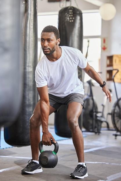 Exercice kettlebell et homme noir faisant du fitness avec un poids avec concentration et motivation Exercices sportifs et athlète masculin africain fort faisant de l'entraînement musculaire ou de l'entraînement dans une salle de sport