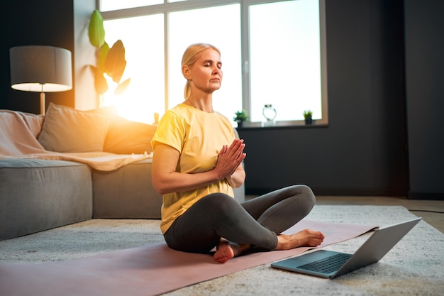 Exercice et méditation Belle femme adulte faisant du yoga en ligne