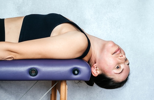 Exercice de la méthode Mckenzie pour soulager les douleurs au cou d'une femme allongée sur la table de massage et l'abaissant il...