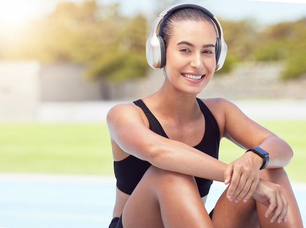 Exercice musical et portrait d'une femme se détendre avec un podcast ou une radio pendant une séance d'entraînement à l'extérieur heureux et joyeux Fitness santé et coureur profiter de la piste audio de bien-être de la motivation tout en se reposant