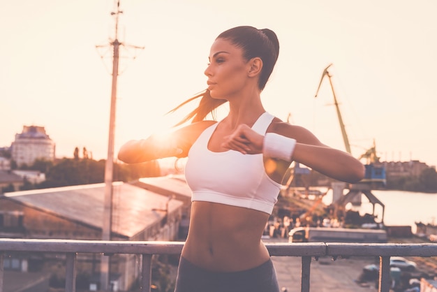 Des exercices d'étirement. Belle jeune femme en vêtements de sport faisant des exercices d'étirement