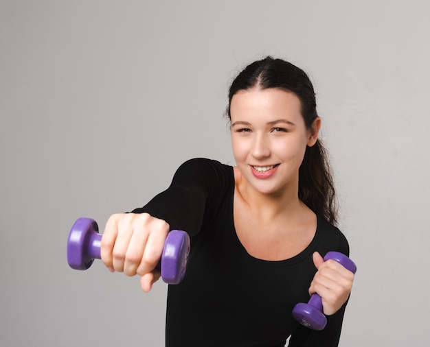 Exercices de modèle de forme physique avec des haltères et boit de l'eau d'une bouteille de sport