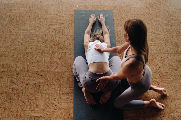Exercices de yoga Un entraîneur personnel enseigne à une femme des cours de yoga dans la salle de sport