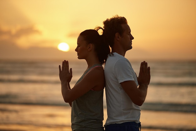 Expérience de l'âme au coucher du soleil Photo d'un couple faisant du yoga sur la plage au coucher du soleil