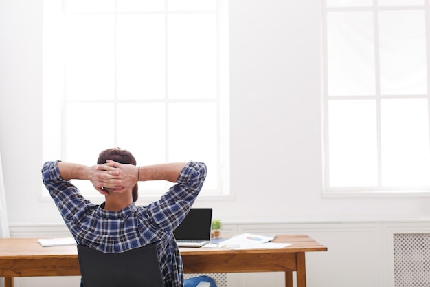 Expérience d'employé de sexe masculin réussie. Jeune manager en vue décontractée de l'arrière avec espace de copie sur la fenêtre. Homme détendu au travail