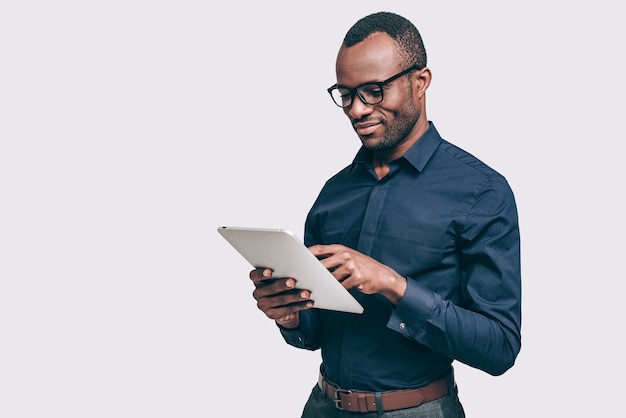 Photo expert en affaires au travail. beau jeune homme africain travaillant sur tablette numérique en position debout