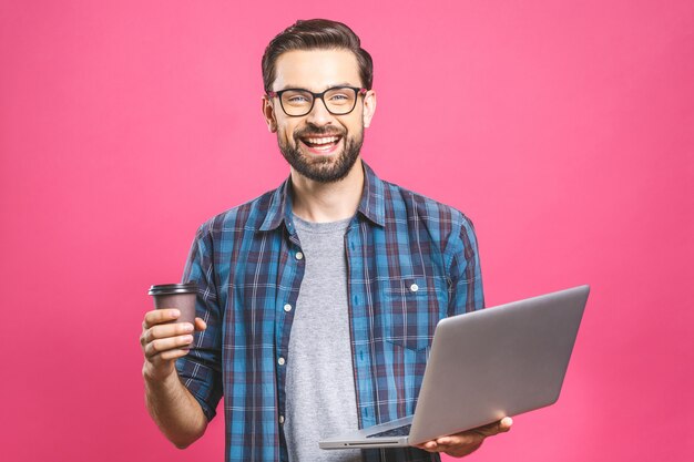 Expert en affaires confiant. Confiant jeune bel homme avec du café en chemise tenant un ordinateur portable et souriant