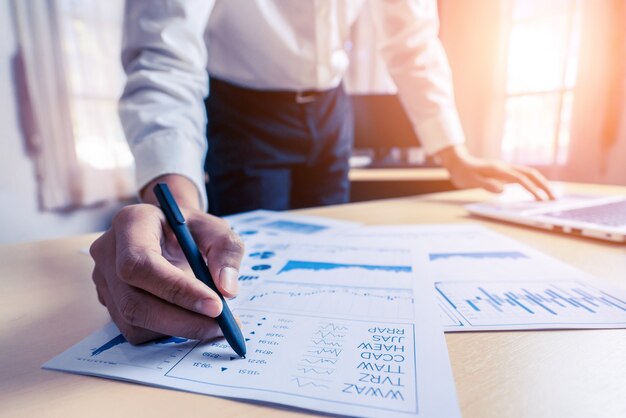 Un expert comptable ou un expert financier analyse le graphique du rapport d'activité et le tableau des finances au siège social. Concept d'économie financière, entreprise bancaire et recherche boursière.