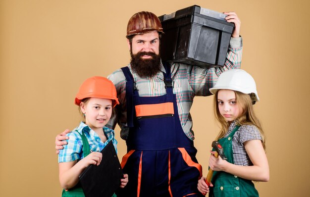 Expert confiant Homme barbu avec des petites filles Père et fille dans l'atelier Travail d'équipe familial Réparation d'outils de l'industrie Réparateur en uniforme assistant de travailleur de la construction de l'enseignement de l'ingénierie