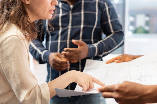 Un expert en immobilier assiste les clients lors d'une visite de l'espace de bureau avec un plan architectural