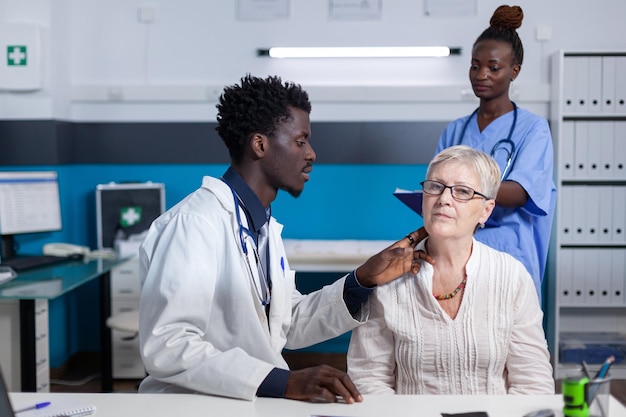 Expert en otologie clinique examinant l'état de l'oreille du patient senior pendant que l'infirmière prend des notes. Médecin de l'hôpital et infirmière dans l'espace de travail de bureau vérifiant l'état de santé de la femme âgée.