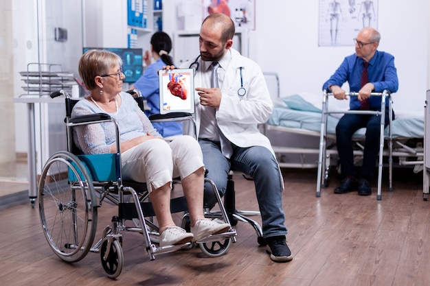 Explication de la maladie coronarienne du médecin à la femme âgée handicapée en fauteuil roulant lors d'un examen médical