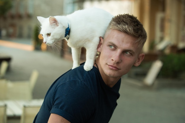 Explorateur curieux. Homme heureux en promenade avec animal de compagnie chat. L'homme musclé tient un chat de race mignon. Heureux propriétaire de chat au look musclé. Le chat se tient sur le dos de son propriétaire.