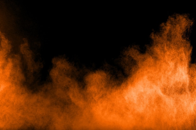 Explosion de poudre orange abstraite sur fond noir.